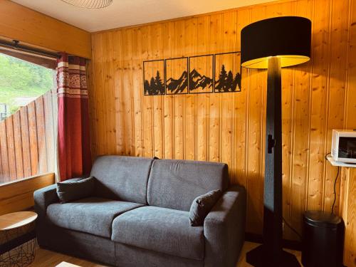 een woonkamer met een bank en een lamp bij Superbe studio Morillon Village / Samoëns in Morillon