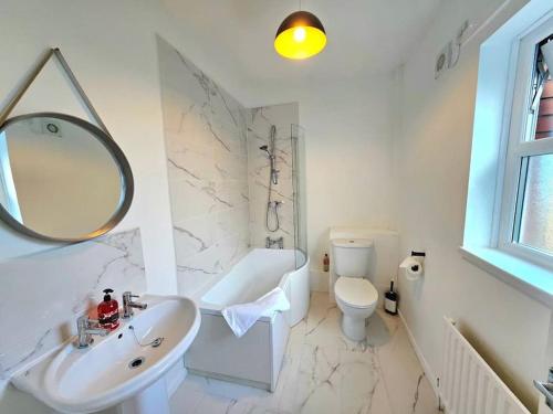 ein Badezimmer mit einem Waschbecken, einem WC und einem Spiegel in der Unterkunft Sensational Stay @Belfast #1 in Belfast