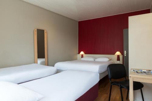 a hotel room with three beds and a desk at The Originals Access, Hôtel Arum, Remiremont in Remiremont