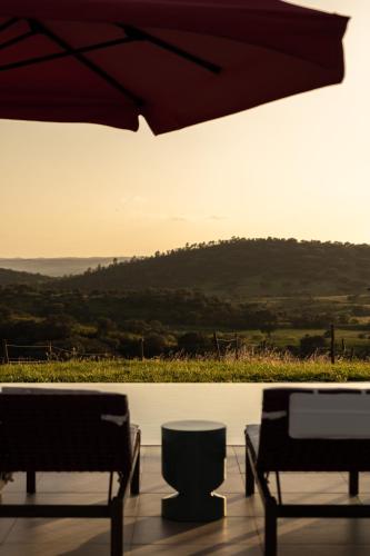 a patio with two chairs and an umbrella at Land of Alandroal in Alandroal