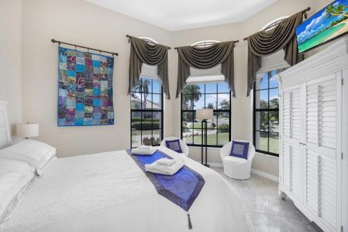 a bedroom with a large bed and two windows at 951 Ruby Court in Marco Island
