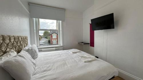 ein Schlafzimmer mit einem Bett und einem TV an der Wand in der Unterkunft Very Spacious 9 Bedroom House-Garden-Parking for 6 in Gloucester