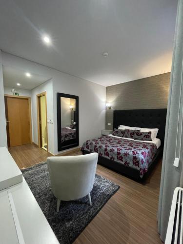 a hotel room with a bed and a white chair at Quinta de VillaSete in Alpendurada