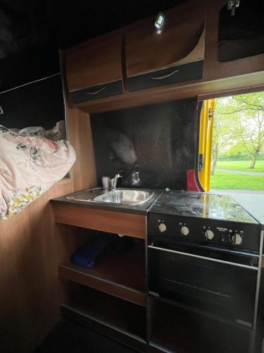 una cocina con fregadero y fogones en una cabaña en Waterside campervan en Mánchester