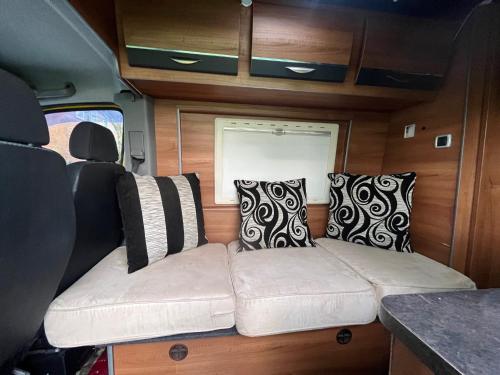 un sofá en la parte trasera de una caravana con almohadas en Waterside campervan, en Mánchester