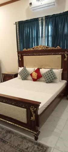 uma cama de madeira com quatro almofadas em SeaView Family Guest House Small Bukhari em Karachi