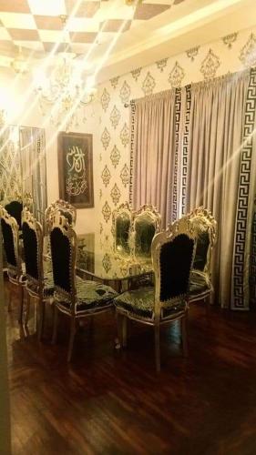 um quarto com cadeiras, uma mesa de vidro e cortinas em SeaView Family Guest House Small Bukhari em Karachi