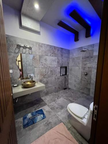 uma casa de banho com um WC e um lavatório com uma luz azul em SeaView Family Guest House Small Bukhari em Karachi