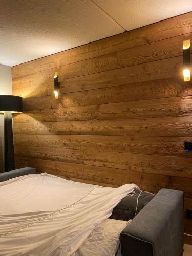 ein Schlafzimmer mit einer Holzwand und einem Bett in der Unterkunft Superbe studio au pied des pistes in La Morte