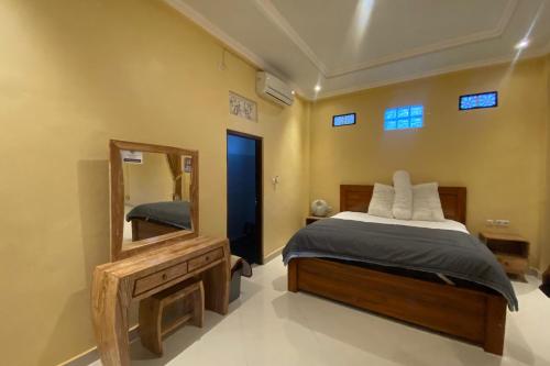 a bedroom with a bed and a mirror at Capital O 93844 Arta Adi Homestay in Bangli