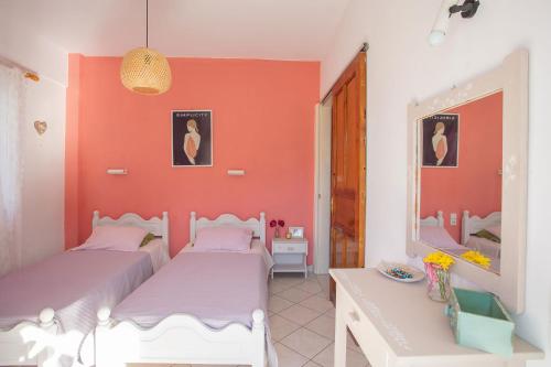 two beds in a room with an orange wall at A4 - Rosemary Apartment in Nydri