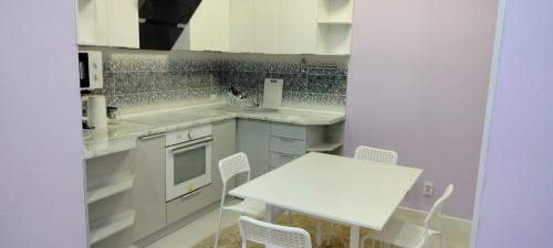 - une cuisine avec une table et une table et des chaises blanches dans l'établissement Сдам в аренду квартиру, à Taldykolʼ