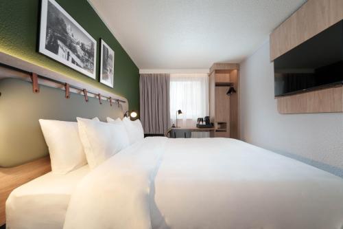 - un grand lit blanc dans une chambre d'hôtel dans l'établissement Campanile Marne la Vallée - Chelles, à Chelles