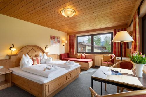 ein Hotelzimmer mit einem großen Bett und einem Tisch in der Unterkunft Gästehaus Rottenspacher in Kössen