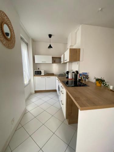 une cuisine avec des armoires blanches et un comptoir en bois dans l'établissement superbe appartement 4 pers. Crozon à 100 m de la plage de Morgat, à Crozon