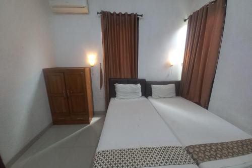 - une chambre avec un grand lit blanc dans l'établissement Capital O 93872 Natura Guest House Syariah, à Purwokerto