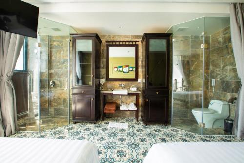 uma casa de banho com um chuveiro, um lavatório e um WC. em Palmy Luxury Beach Phú Quốc em Duong Dong