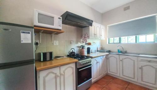 a kitchen with white cabinets and a stove and a microwave at Koo Karoo Guest Lodge and Self Catering in Montagu