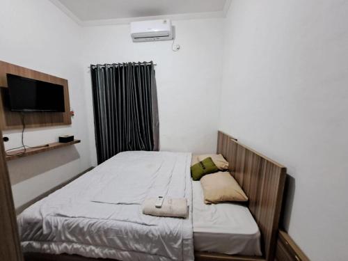 a bed in a room with a tv and a bed sidx sidx sidx at OYO 93870 Damai Guest House Cirebon in Cirebon