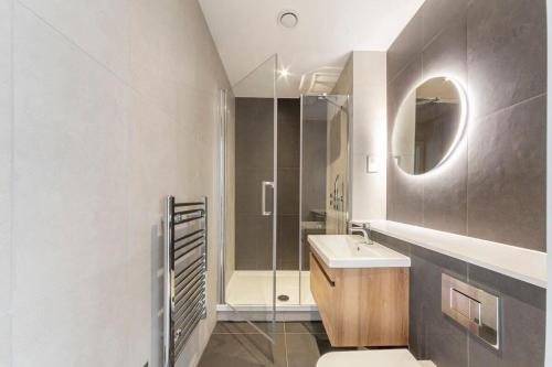 a bathroom with a sink and a shower with a mirror at Bright Contemporary Studio in East Grinstead in East Grinstead