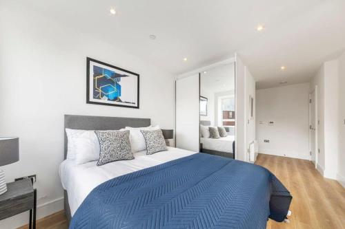 um quarto com uma cama grande e um cobertor azul em Bright Contemporary Studio in East Grinstead em East Grinstead