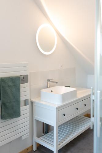 une salle de bain blanche avec un lavabo et un miroir dans l'établissement Les Frangines - maison de ville avec jardin Ault, à Ault