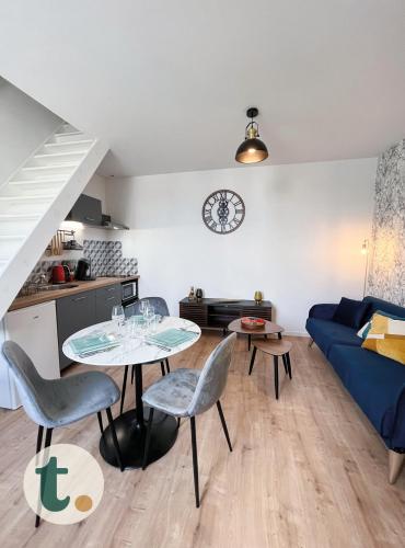 ein Wohnzimmer mit einem Tisch und einem blauen Sofa in der Unterkunft Tranquiloue - Idéal Duplex T2 - 8min du Puy du Fou in La Verrie