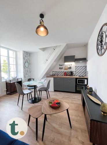 ein Wohnzimmer mit einem Tisch und einer Küche in der Unterkunft Tranquiloue - Idéal Duplex T2 - 8min du Puy du Fou in La Verrie