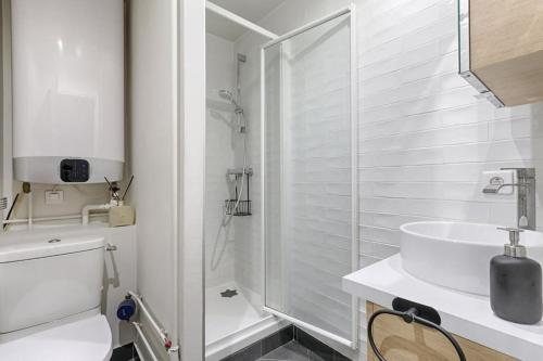 een witte badkamer met een wastafel en een douche bij Résidor - Warm and bright 4P apartment! in Boulogne-Billancourt
