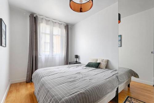 een witte slaapkamer met een bed en een raam bij Résidor - Warm and bright 4P apartment! in Boulogne-Billancourt