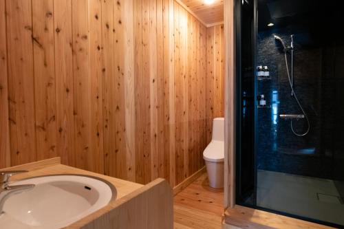 uma casa de banho com um lavatório, um chuveiro e um WC. em Nunoya Ryokan em Matsumoto