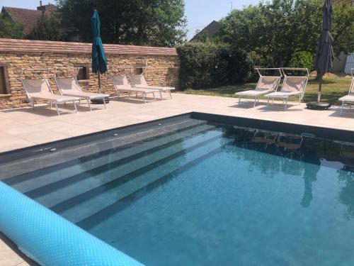 a swimming pool with chairs and umbrellas at Le Clos n°5 in Villy-le-Moutier