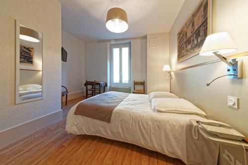 a bedroom with a large bed and a lamp at Contact Hôtel du Commerce et son restaurant Côte à Côte in Autun
