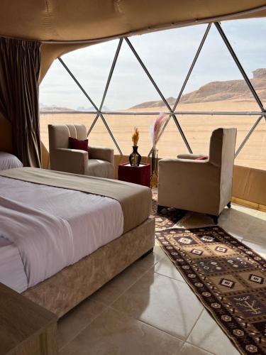 a bedroom in a tent with a bed and chairs at Wadi Rum Rose Luxury camp in Wadi Rum