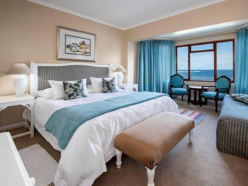 a bedroom with a large bed and a table and chairs at Sandbaai Country House in Hermanus