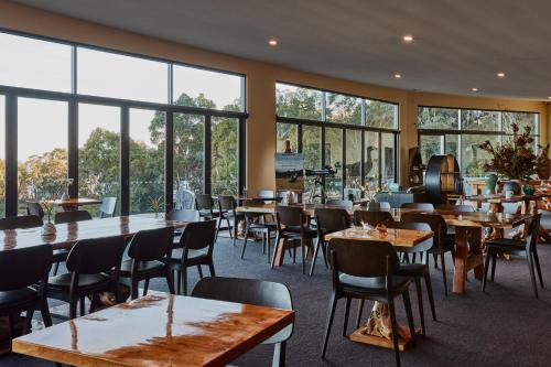 un restaurante con mesas, sillas y ventanas grandes en Freycinet Resort, en Coles Bay