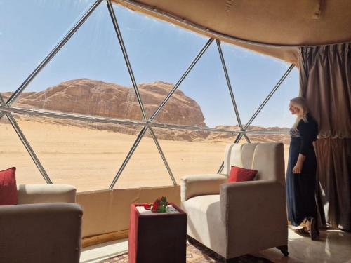 a woman standing in a tent looking out at the desert at Wadi Rum Rose camp in Wadi Rum