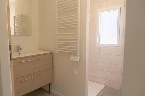 baño blanco con lavabo y ventana en La Vie En Gîte (La Taïga), en Sainte-Florence