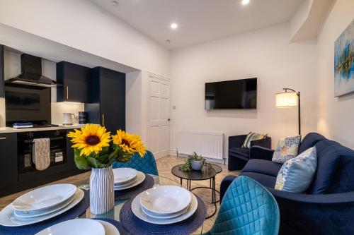 ein Wohnzimmer mit einem blauen Sofa und einem Tisch in der Unterkunft Willowstay - SJA Stays - Modern 2 Bed Apartment in Aberdeen