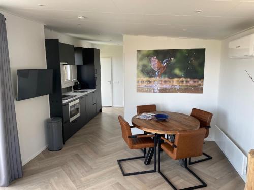 a kitchen with a table and chairs in a room at Vogelvrij, vakantie woning met landelijk uitzicht en geheel omheinde tuin in Burgerbrug