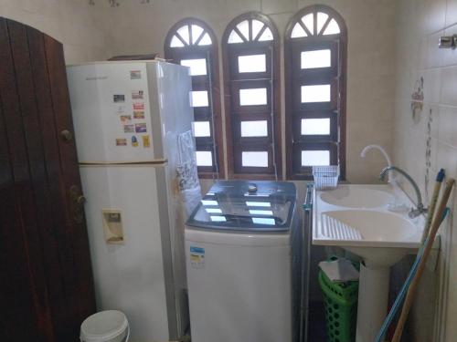 a kitchen with a white refrigerator and a sink at Confortável, 1min da praia a pé in Niterói