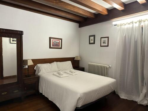1 dormitorio con cama blanca y espejo en Casa Boado, en Boimorto