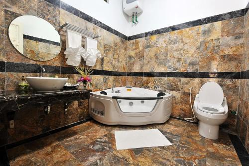 a bathroom with a tub and a toilet and a sink at Hoàng Long Resort Villa in Xóm Chua Thanh