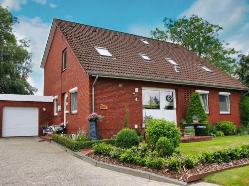 een rood bakstenen huis met een witte garage bij Ferienwohnung Heijenga, 45223 in Jemgum