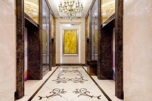 a hallway with a chandelier and a tile floor at HT Legend Hotel Changgang Metro Station Exit F - Free Shuttle Bus to Canton Fair Complex During Canton Fair Period in Guangzhou