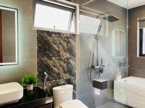 a bathroom with a shower and a toilet and a sink at Dahlia villa - Sonasea Vân Đồn Harbor city in Cái Rồng
