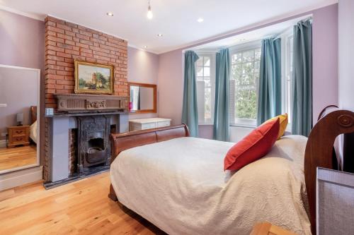 1 dormitorio con 1 cama grande y chimenea en 4 bed 3 bath refurbished Norbury Apt, en Thornton Heath