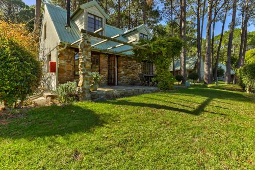 a stone house with a green roof and a yard at Houtkapperspoort Mountain Cottages in Cape Town