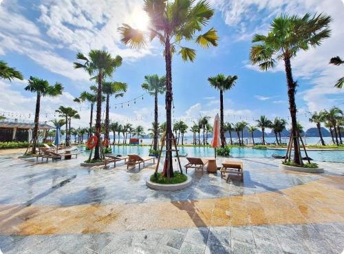 a resort with a pool with palm trees and benches at Dahlia villa - Sonasea Vân Đồn Harbor city in Cái Rồng