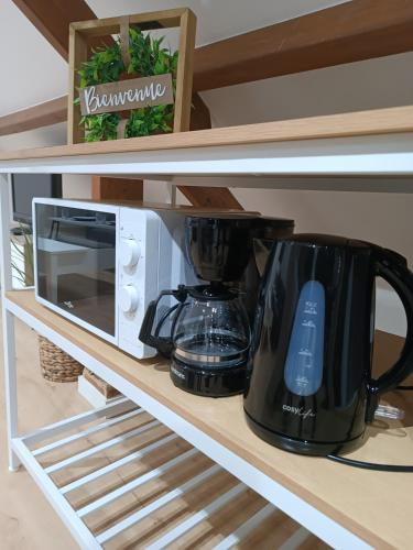 une cafetière et un four micro-ondes sur une étagère. dans l'établissement logement cosy et au calme proche Paris Aéroport CDG DISNEY ASTERIX, à Fontenay-en-Parisis